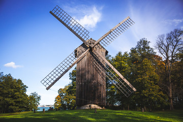 Fototapeta na wymiar Traditional windmill wooden house on a green grass and under a clear blue sky