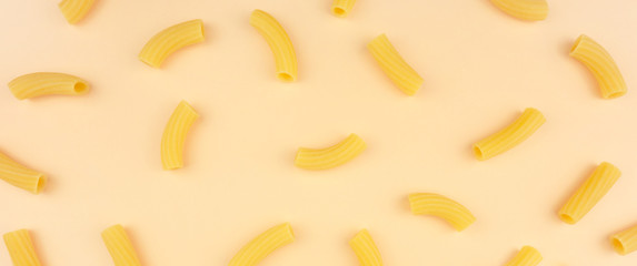 Macaroni pattern on ocher background. Italian food. Pasta composition. Flat lay layout.