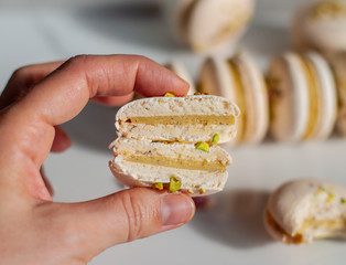 Hand holds two halves of macaron with pistachio ganache