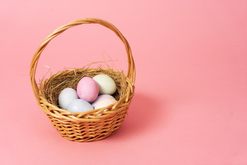 Happy easter: basket with colorful eggs on a pink background.