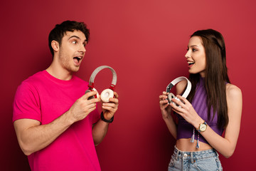 beautiful excited couple holding headphones on red