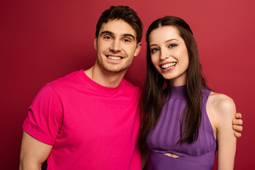 beautiful smiling young couple looking at camera on red