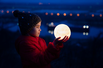 teenager girl in cap and jacket holds a full moon