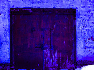 Rusty locked iron gates tinted in deep blue.