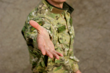 Outstretched hand of a military man. Isolated on brown background.