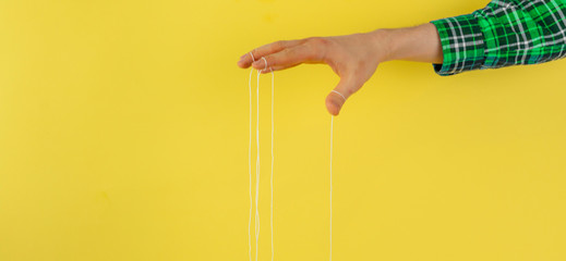 puppeteer's hand with ropes on fingers control the people mind concept wide web banner