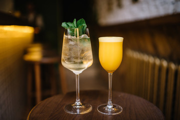 mint spritz and orange sour cocktails on a wooden table