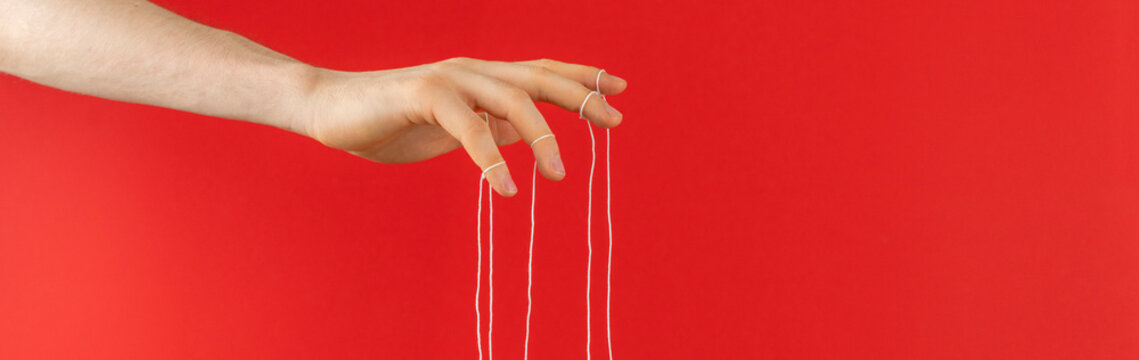 puppeteer's hand with ropes on fingers control the people mind concept wide web banner