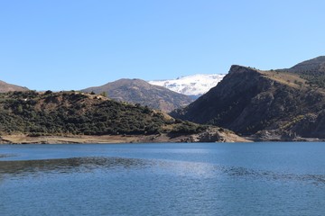 Fototapeta na wymiar Paisaje con lago azul, montañas verdes y con nieve