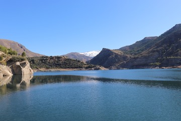 Paisaje con lago azul, montañas verdes y con nive