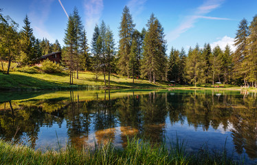 Wonderful sunny landscape in Alps. Scenic image of fairy-tale woodland in sunlit with beautiful reflections in asure water. Amazing nature scenery. Natural background.