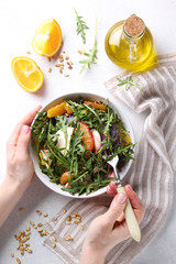 Healthy food. Fresh salad with arugula, mozzarella, baked beetroot, oranges and pine nuts in the bowl with hands. Background image, copy space