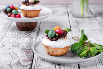 Easter cupcake topped with multicolored marzipan eggs, chocolate nest and marshmallow cream