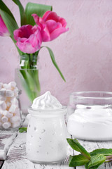 Marshmallow creme in glass jars on the white wooden table