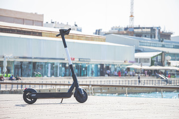 Black electric scooter parking on a deck at Tel Aviv Port commercial district on a summer sunny day