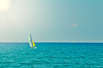 Small personal sailboat sailing in the open flat sea on a summer day