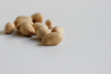 Pistachio nuts have not opened fully on a white background.