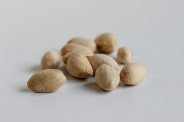 Pistachio nuts have not opened fully on a white background.