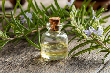 A bottle of rosemary essential oil with fresh rosemary