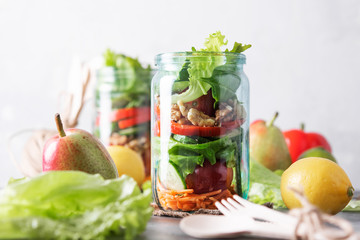 Healthy homemade mason jar salad with fresh pear tomatoes, carrots and herbs. Vegetarian concept.
