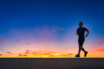 Fototapeta na wymiar Man running sprinting on road. fit male fitness runner during outdoor workout with sunset background