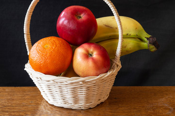 Fruits in light basket on wooden table