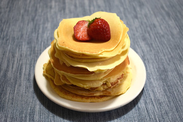 stack of pancakes with maple syrup and fruits
