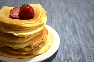 stack of pancakes with maple syrup and fruits