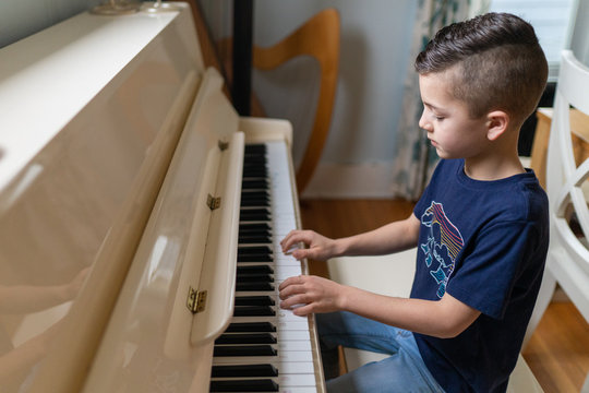 young boy playing the piano at home