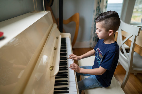young boy playing the piano at home