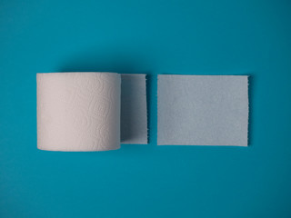 Toilet paper roll and torn sheet on a blue background top view with copy space.