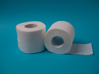 Two rolls of white toilet paper on a blue background close-up.