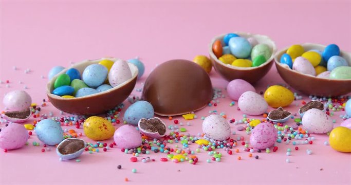 Epic footage of Chocolate Easter Eggs. Small candies are falling on bright background.
