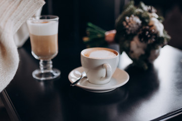 the bride and groom sit at a table in a cafe with coffee and hold hands