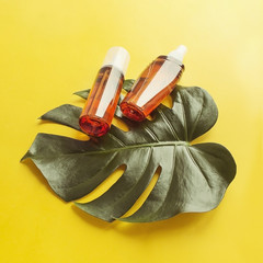 Summer sunscreen. Set of cosmetic bottles on a light background with green leaves of a monster....