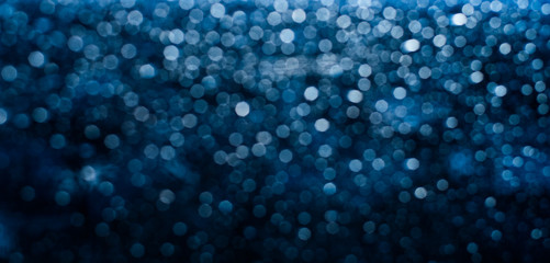 Blue lights with highlights sparkles on a dark background. Out of focus, blues. Festive atmosphere of lights in the night. Bokeh texture for overlay on pictures. Web banner backdrop.