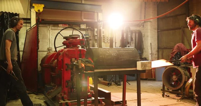 Bladesmiths working with hot metal at kiln and cylinder