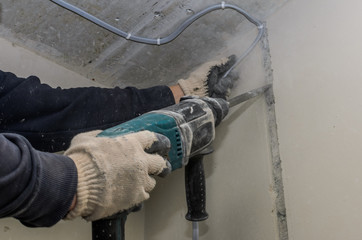 Worker breaks a concrete wall with a perforator chisel