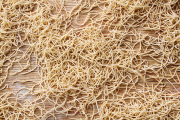 Fresh thin dried homemade soup noodles on a wooden board. Close-up. Top view. Background. Texture.