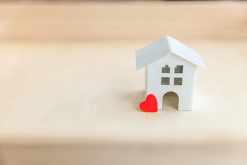 Obraz na płótnie Canvas Miniature toy model house with red heart on wooden backdrop. Eco Village abstract environmental background. Real estate mortgage property insurance sweet dream home ecology concept