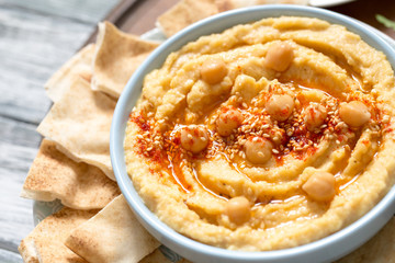 A bowl of creamy homemade hummus with olive oil and pita chips. traditional vegan healthy meal
