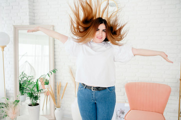 Happy plus size model in jeans and white t-shirt, tosses hair lifestyle. Young plump woman in...