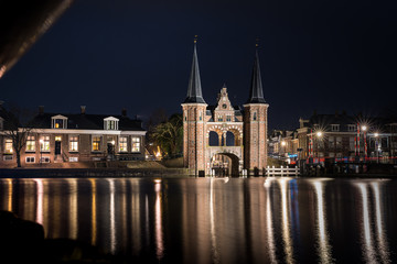 Fototapeta na wymiar The famous historical 'Waterpoort' in the city of Sneek at night with reflections in the canal - Sneek, Friesland, The Netherlands