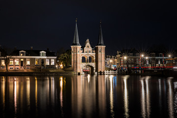 Naklejka na ściany i meble The famous historical 'Waterpoort' in the city of Sneek at night with reflections in the canal - Sneek, Friesland, The Netherlands