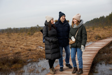 a guy and two girls walk in nature. Friends laugh and smile