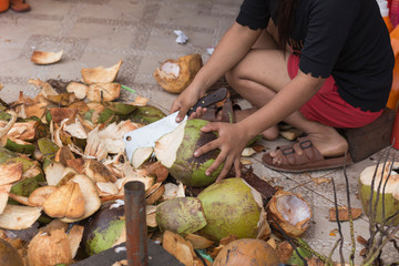Woman strips and cuts coconuts at a Kratie street stall in Cambodia