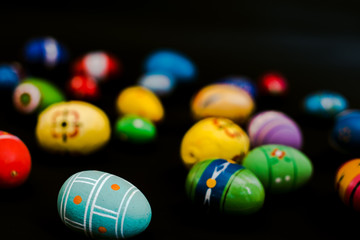 multicolored wooden eggs on black background