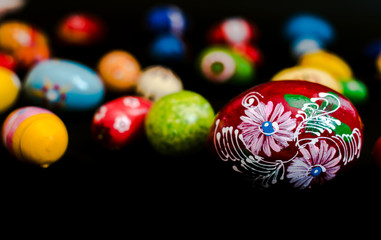multicolored wooden eggs on black background