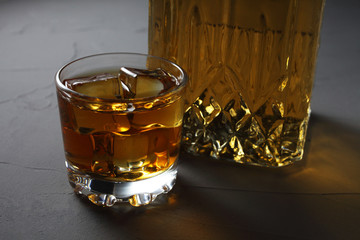 Glass rum with ice, carafe with rum on a concrete background close-up