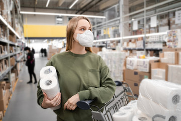 Fototapeta na wymiar Toilet paper shortages amid panic throughout the world due to the influenza epidemic and the COVID-19 coronavirus pandemic. Woman in a store buys toilet paper. People, social problems, quarantine